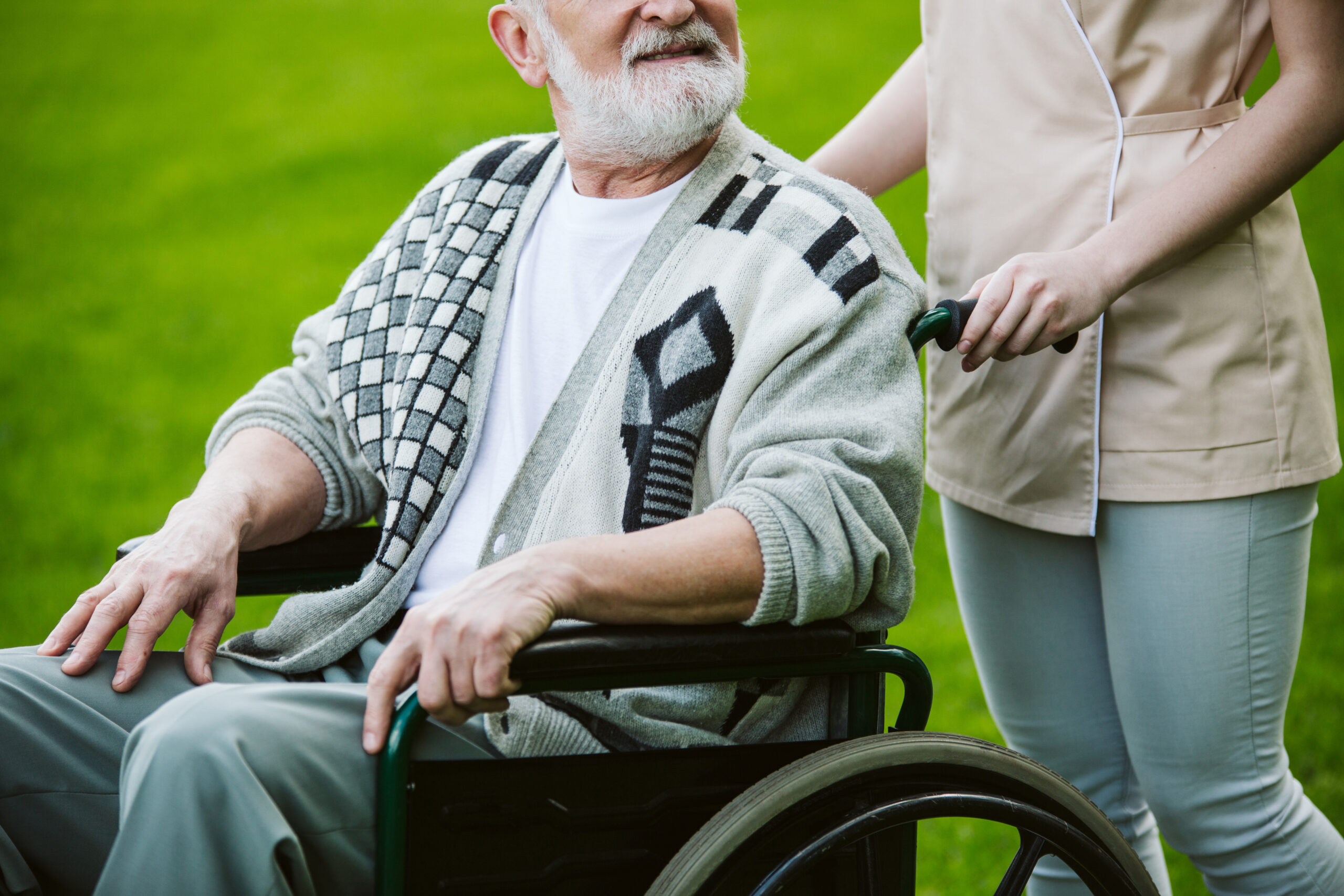 Nurse with patient on the wheelchair walking in the gardden