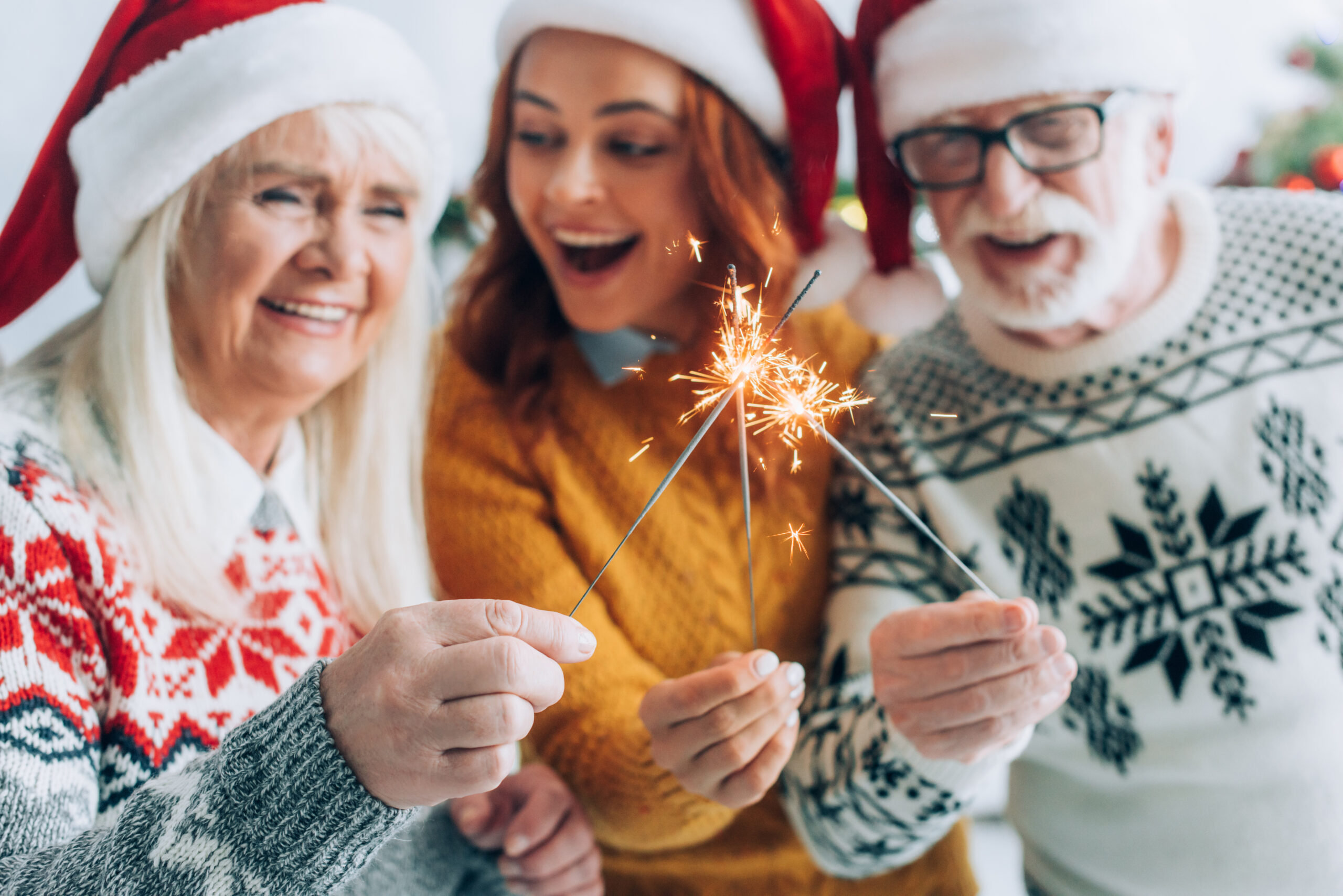 selective focus of senior couple with daughter lighting sparklers on christmas