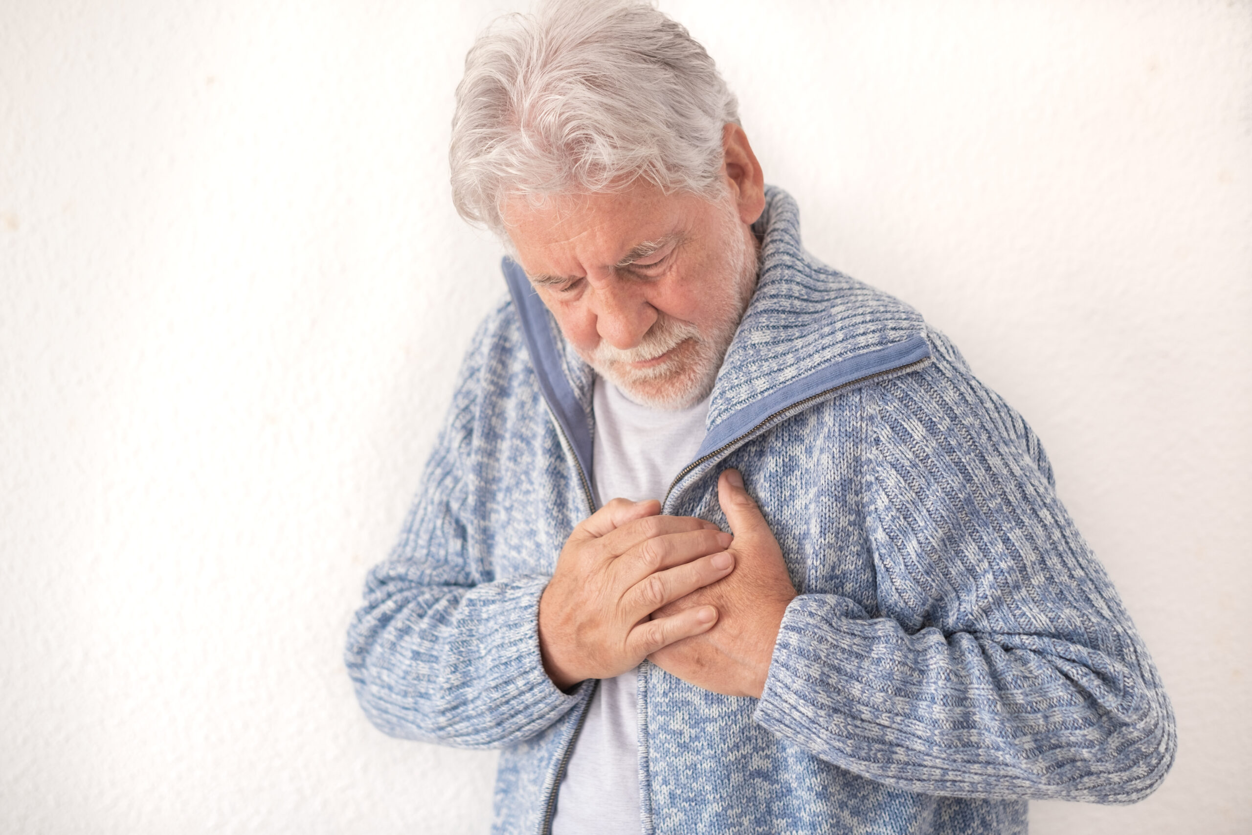 Senior white haired man suffering for heart attack at home. Elde