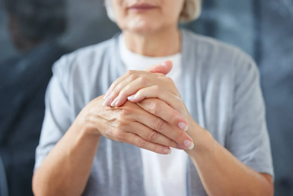 seniorka trzymająca się za obolała palce