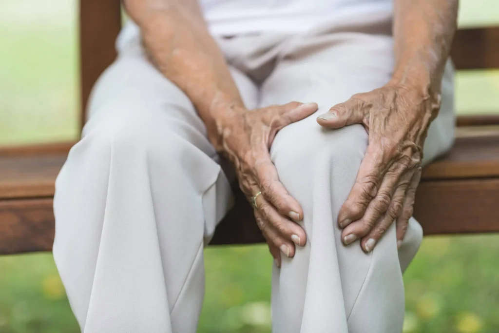 seniorka trzymająca się za bolące kolano